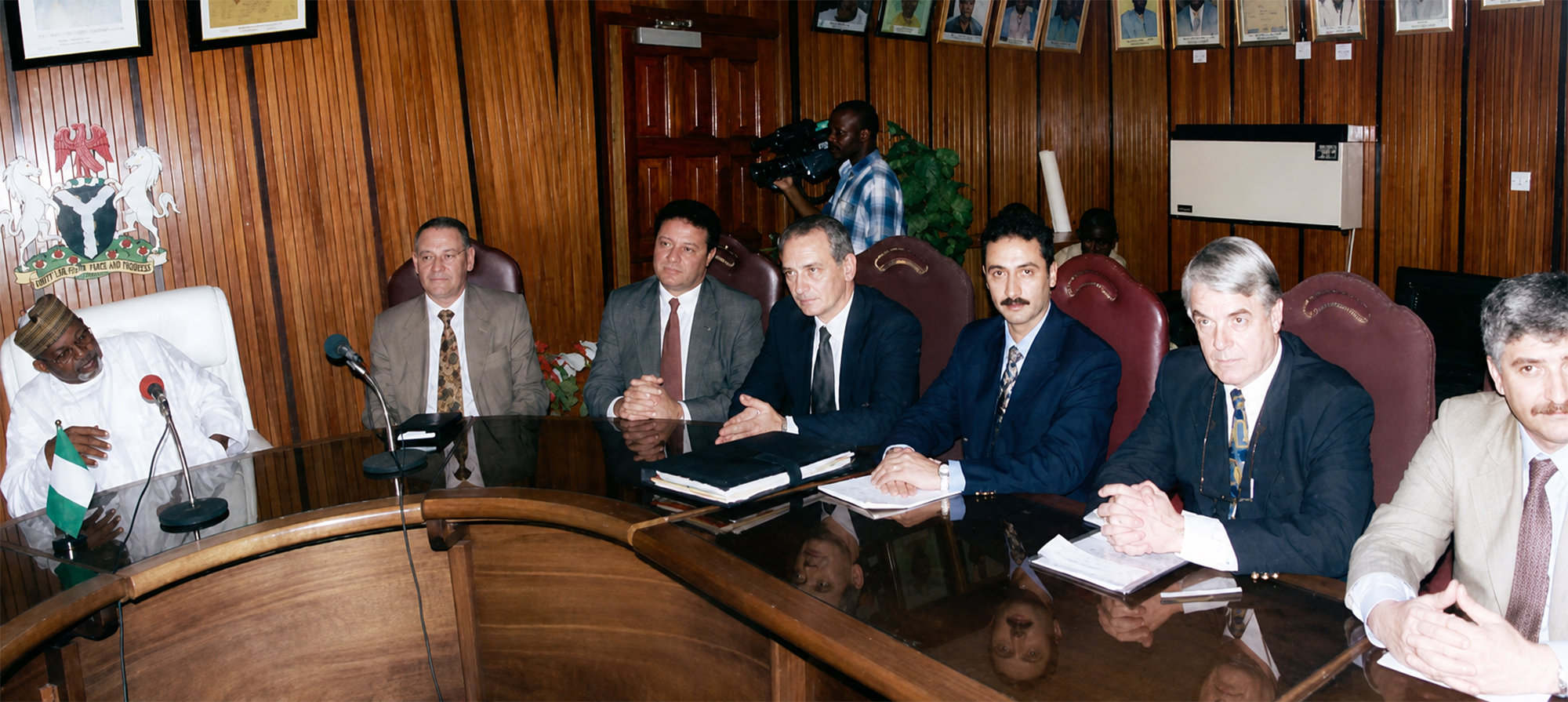 Reunión institucional en una sala revestida de madera con autoridades nigerianas en Abuya durante la Travesía Nigeriana