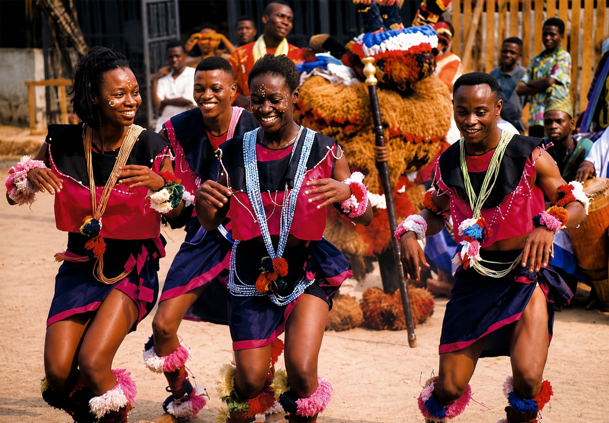 Grupo de danzantes con vestimenta rosada y azul bailando junto a una figura enmascarada en Sokoto durante la Travesía Nigeriana