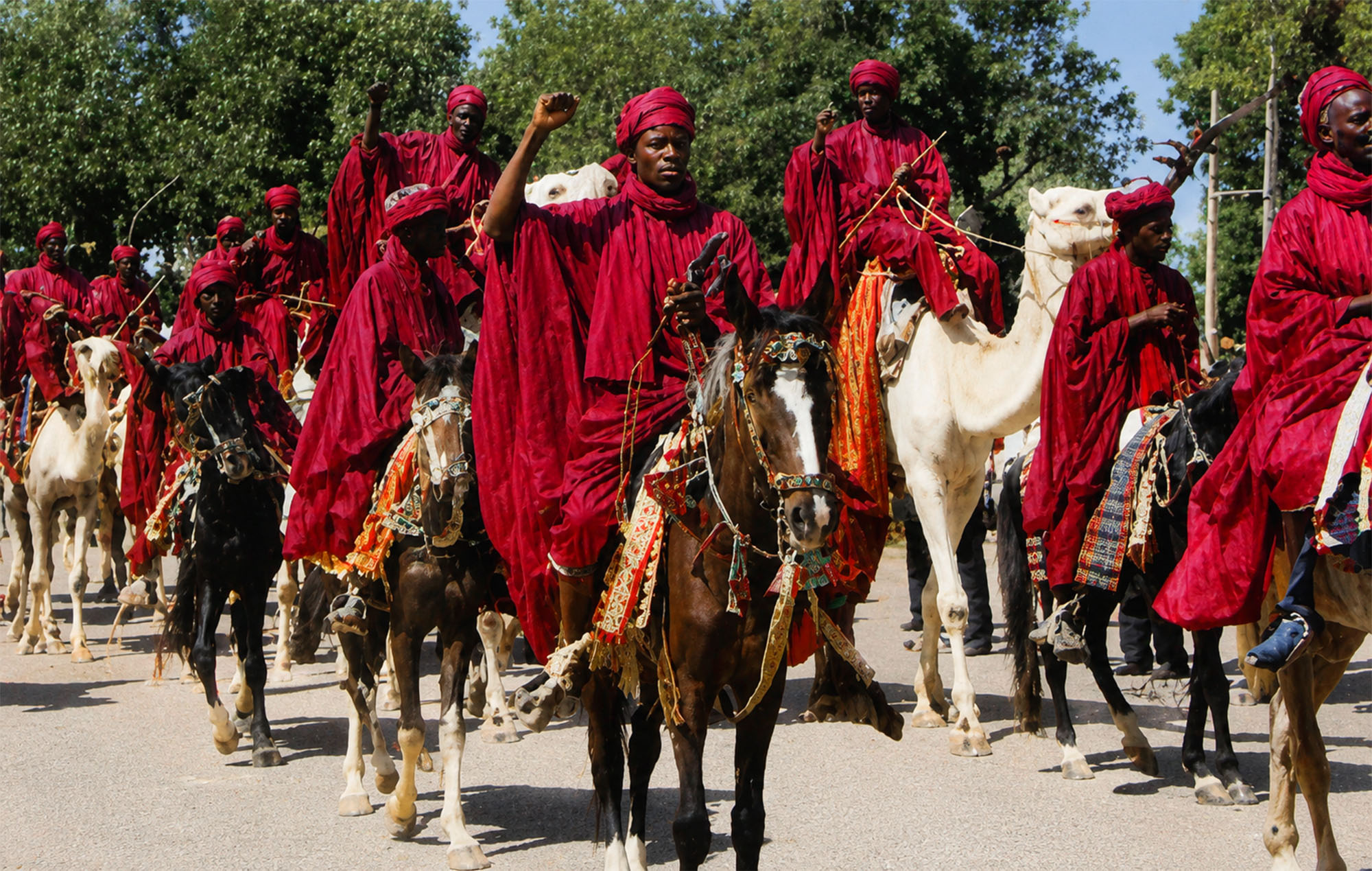 Jinetes con túnicas rojas a caballo y camello durante una procesión ceremonial en Kano durante la Travesía Nigeriana