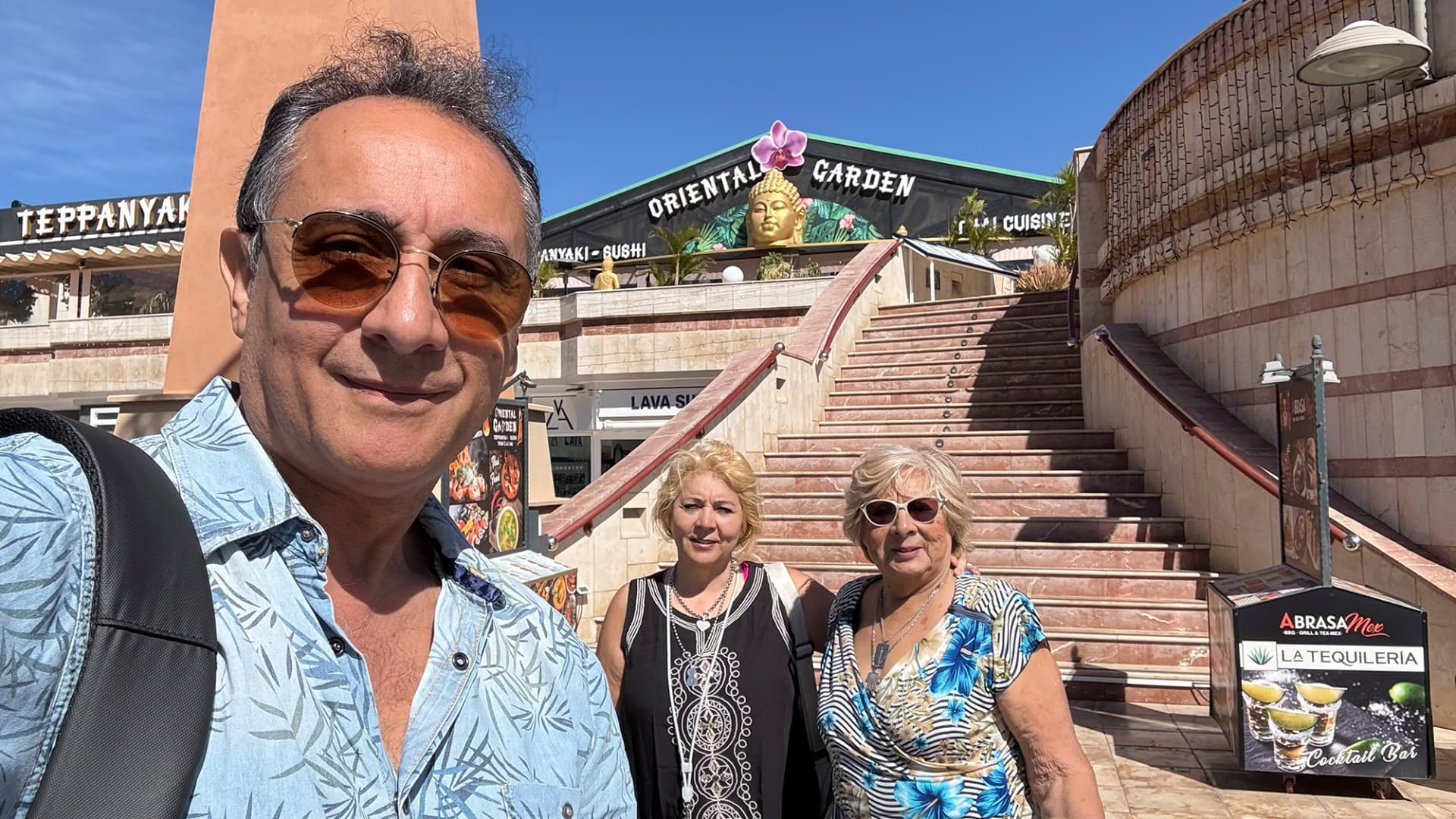 Ricardo Adrián Pena acompañado por dos personas frente a un local del sur de Tenerife