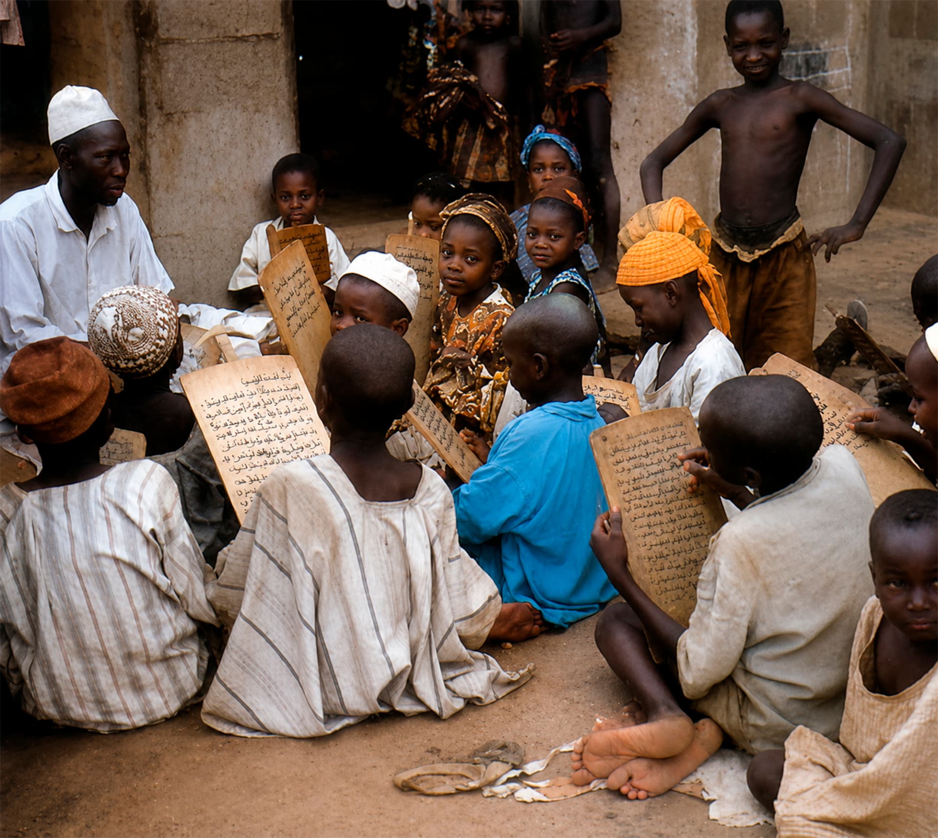 Niños estudiando textos en tablillas junto a un maestro en Kano durante la Travesía Nigeriana