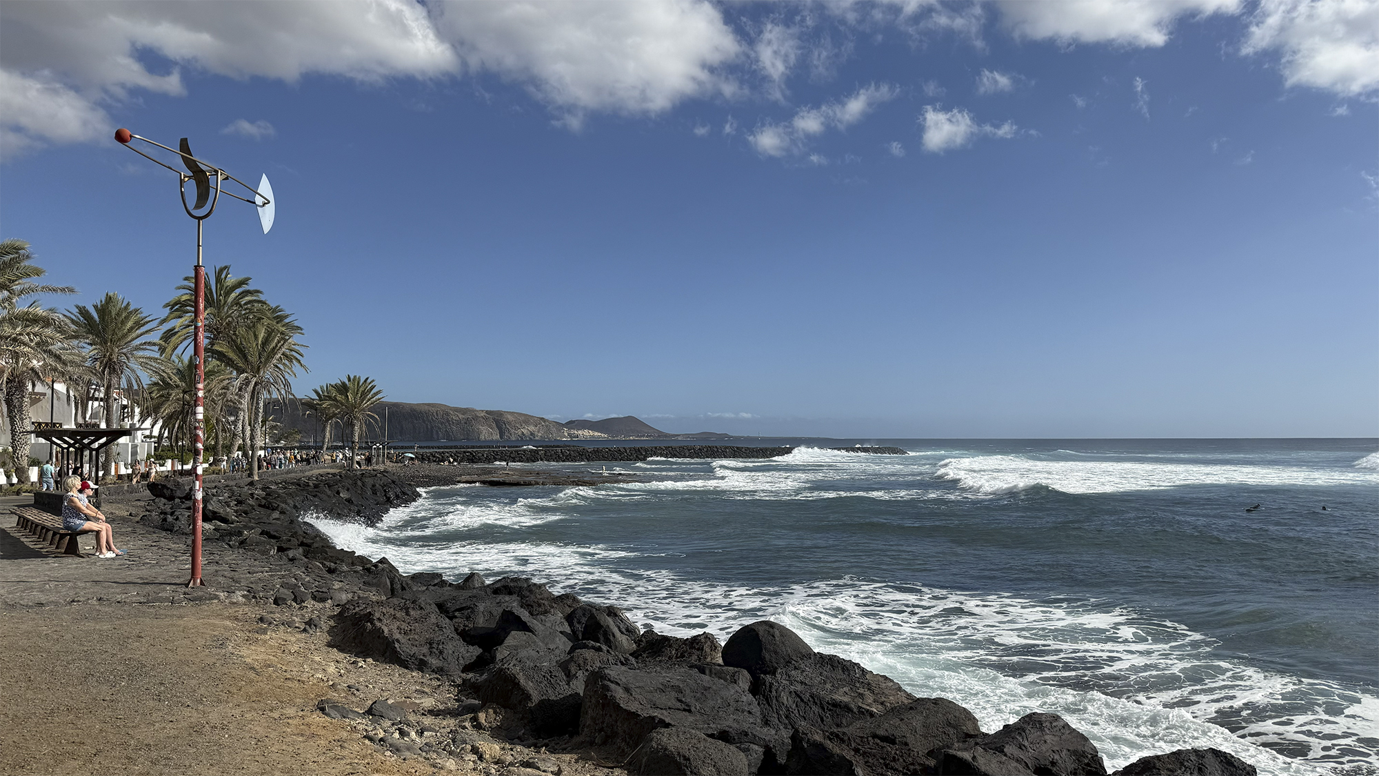 Costa rocosa volcánica con oleaje atlántico, palmeras y cielo azul