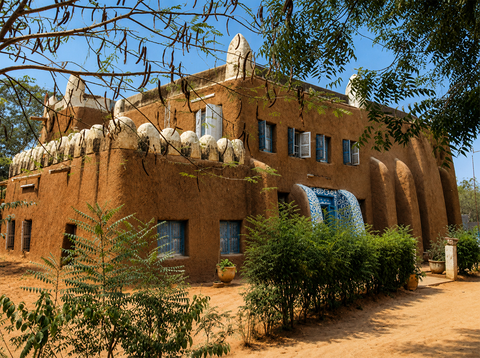 Casa tradicional de adobe con pináculos encalados y postigos azules en Kano durante la Travesía Nigeriana