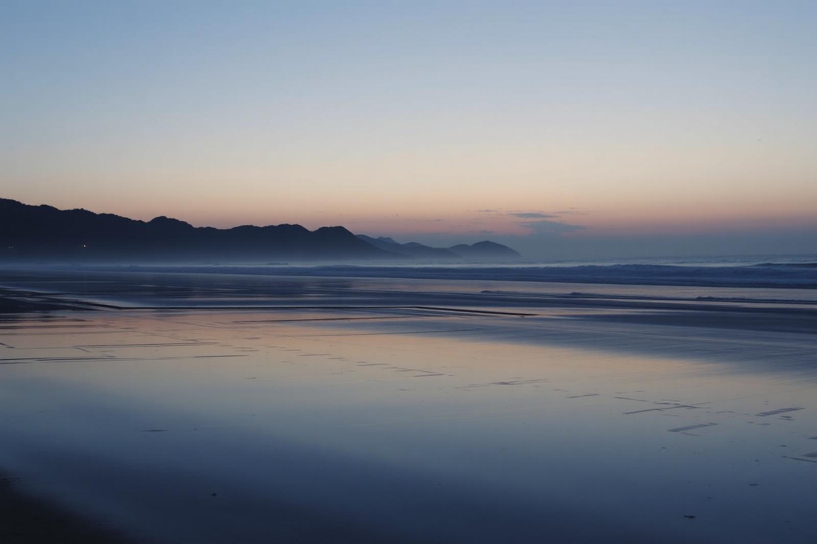 Bahía en calma al anochecer con montañas recortadas en el horizonte