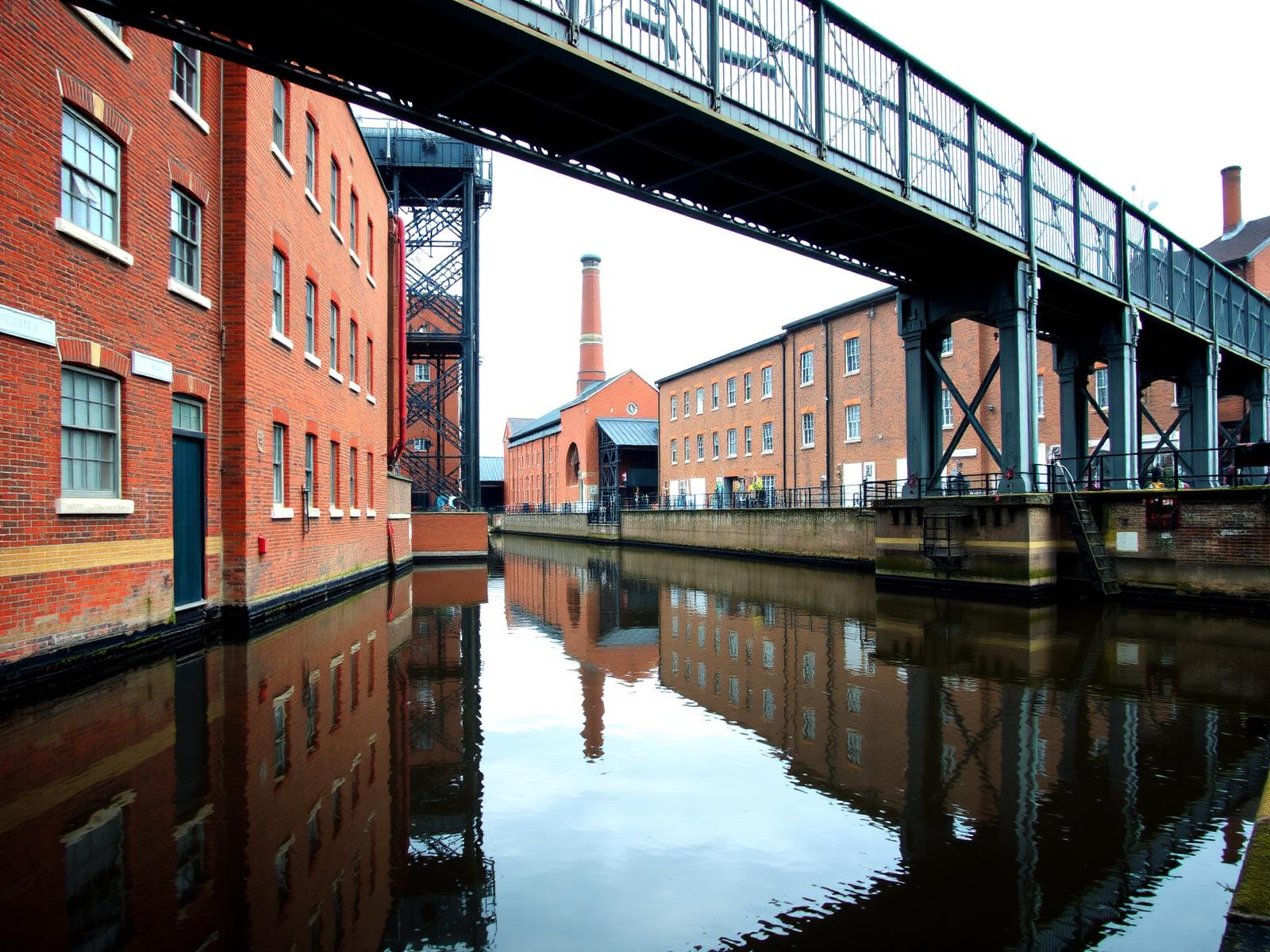 Canal industrial de Birmingham con almacenes de ladrillo y pasarela de hierro